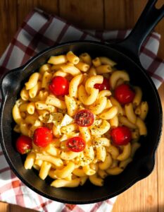 Comfort food at its best: a hearty serving of macaroni pasta in a rich cheese sauce, enhanced with juicy tomatoes and a touch of black pepper